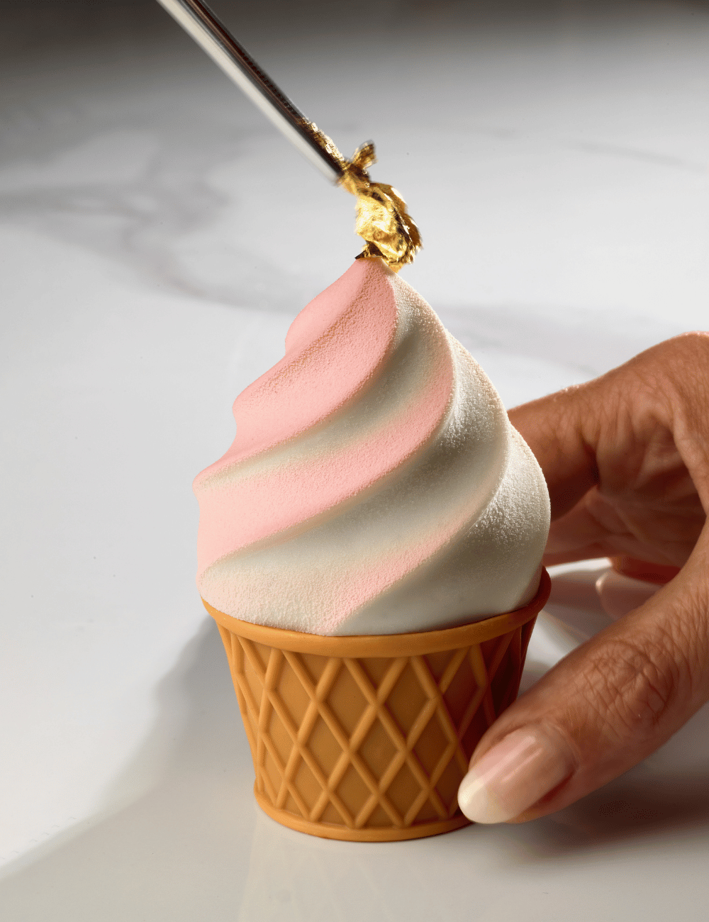 Gros plan sur l'application de la feuille d'or et le tourbillon bicolore du dessus Gelato