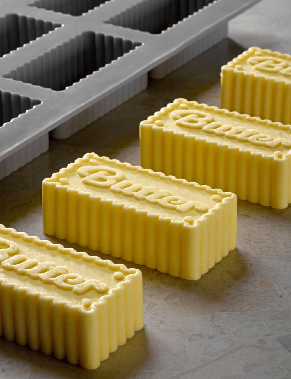 Gros plan sur les plaquettes de beurre Butter : lettrage calligraphié, bordure festonnée et flancs cannelés