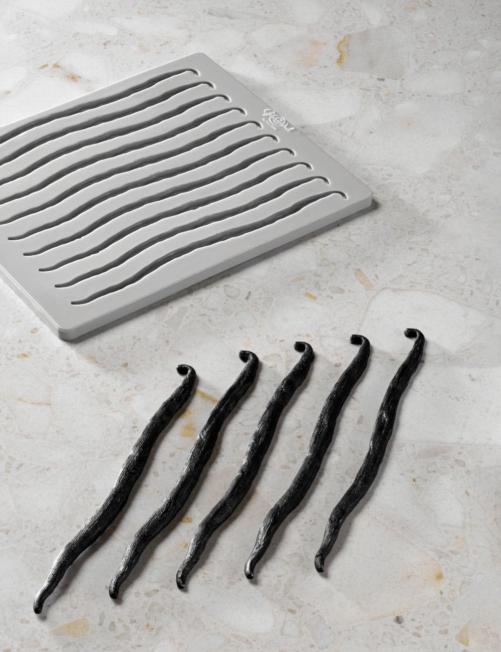 Moule en silicone Vanilla vu du dessus, à côté de 5 décors en forme de gousses de vanille